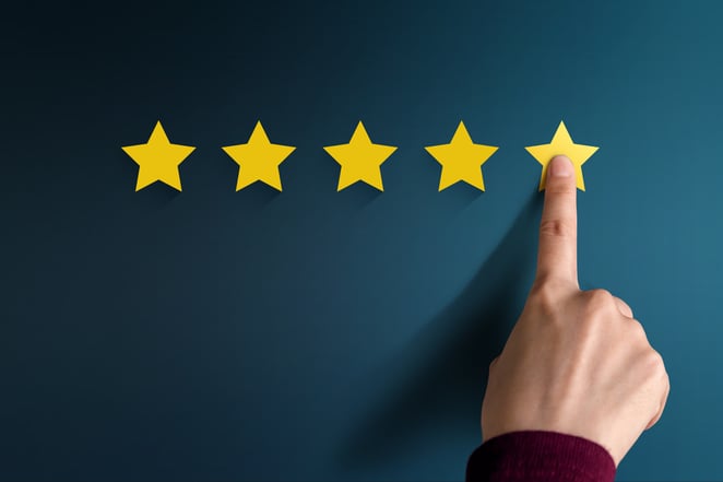 5 stars on a board with a finger on 5th star