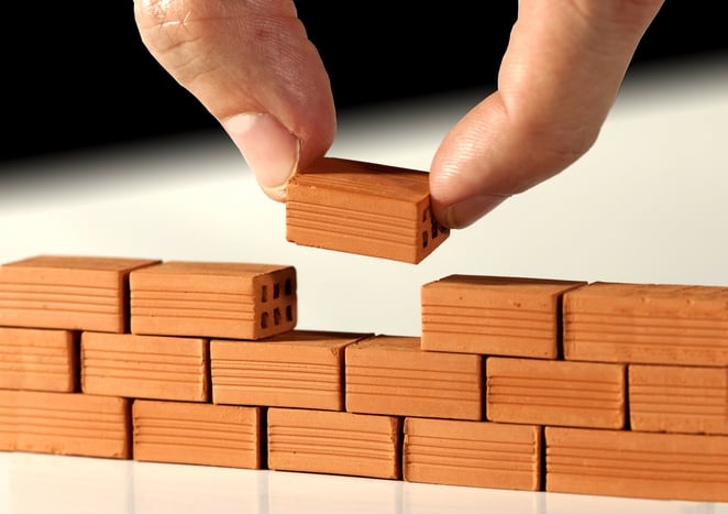 hand with little blocks building a wall